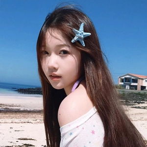 Blue starfish hair clip accessory styled on wavy hair with a scenic beach background