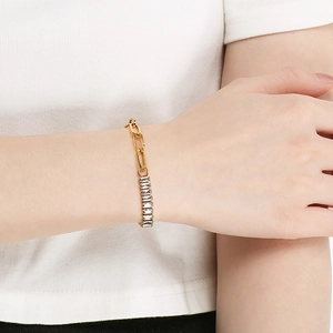 Detail of gold chain bracelet with baguette-cut clear gemstone on model wrist