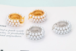 Detail of wide hoop earrings with three rows of white pearls in gold and silver finish