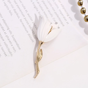 Detailed view of an elegant white tulip brooch with golden metal leaves on a vintage book