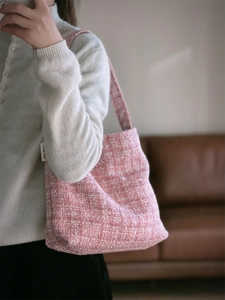 Gros plan sur la texture du tissu en tweed rose d'un sac à bandoulière tressé avec étiquette