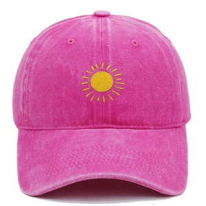 Close-up of yellow sun embroidery on a washed rose pink cotton vintage baseball cap