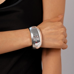 Close-up of a wide polished silver cuff bracelet with a minimalist geometric design