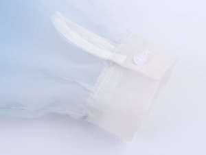 Detail of sheer gradient blue organza shirt cuff with white button and refined texture