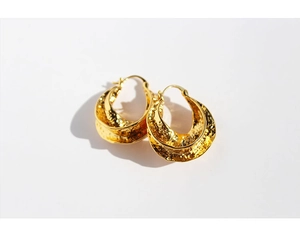 Detailed view of gold hoop earrings featuring vintage hammered texture and metallic luster