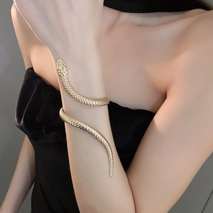 Detailed view of a golden snake arm cuff with scale texture on a female model arm