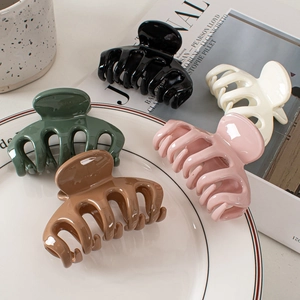 Glossy minimalist hair claws in black, white, pink, and green on a decorative plate