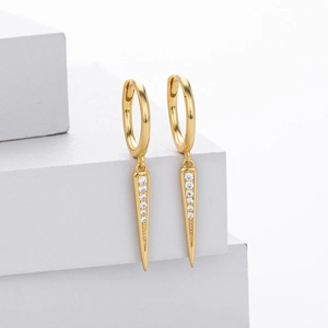 Close-up of golden drop earring with tapered cone pendant and white cubic zirconia stones