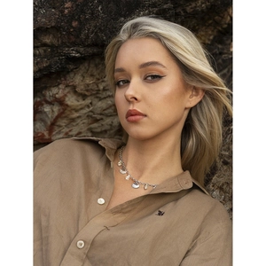 Detail of silver shell and pearl pendant necklace worn with brown linen shirt