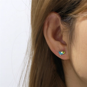 Close-up of a model wearing a unique blue bird-shaped silver stud earring on ear