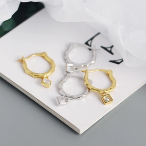Detailed view of irregular S925 silver hoop earrings with diamond charms in gold and silver