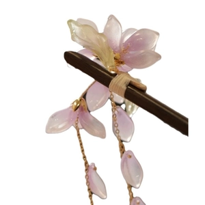 Eleganter chinesischer Haarnadel mit lila Blüten und goldenen Quasten auf dunklem Holz
