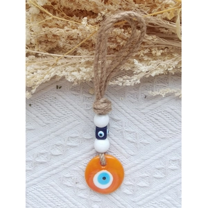 Detail of handmade twine woven Evil Eye pendant with orange disk and blue eye charm