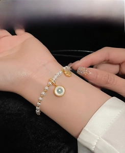 Détail d'un bracelet en perles avec pendentif bleu rond et breloque tournesol dorée