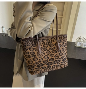 Detail of large leopard print tote bag with brown leather straps and canvas texture