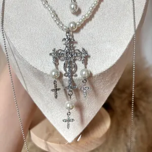 Macro shot of silver cross pendant necklace with baroque pearls and crystal details