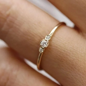 Exquisite gold ring featuring three round zircons in a classic bezel setting on finger