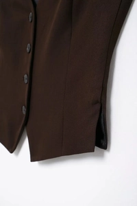 Détail du gilet marron foncé avec fente latérale et texture de fermeture à boutons