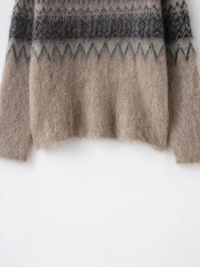 Detailed macro view of the fuzzy knit texture and geometric pattern on the sweater hem