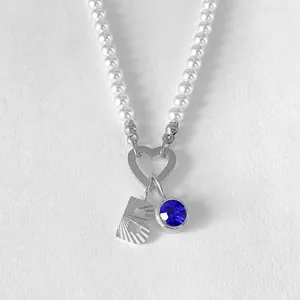 Vue détaillée d'un collier de perles avec fermoir cœur, lettre B et pierre bleue.