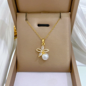Detail of gold pearl necklace with floral zircon pendant on elegant white satin