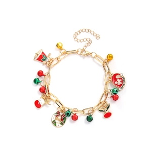 Detailed shot of Christmas charm bracelet with gold chain, bell, and stocking pendants