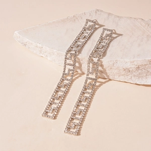 Macro detail of silver geometric Greek key drop earrings with sparkling tassels