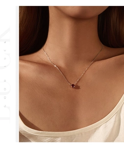 Close-up of a s925 silver necklace with red garnet pendant on a female collarbone