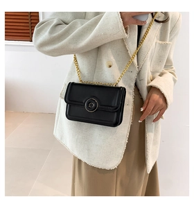 Detail of a chic black rectangular shoulder bag featuring a gold chain strap and metal buckle