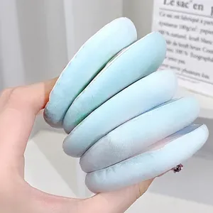 Soft light blue plush cosmetic powder puff set for makeup held by hand in close-up