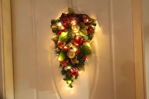 Detail of Christmas swag with red gold balls, buffalo plaid bow, and warm LED lights