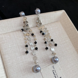 Detail of tassel earrings with grey pearls, silver chains, and black crystal beads
