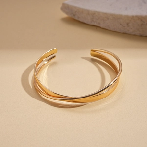 Detailed close-up of golden multi-layer twisted open bangle with polished mirror finish