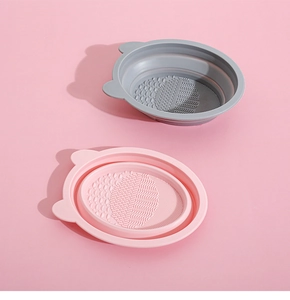 Detailed view of pink and grey foldable silicone brush cleaning bowls with textured bottom