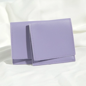 Close-up of lavender PU leather drawstring pouches with flap on elegant white silk cloth