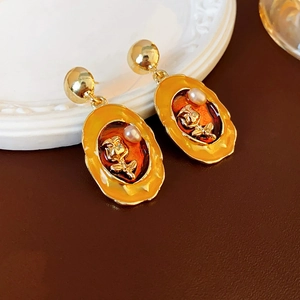 Macro detail of vintage enamel earrings with golden rose carving and white pearl accent