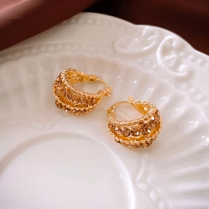Detail of gold hoop earrings with champagne crystals on an elegant ceramic plate