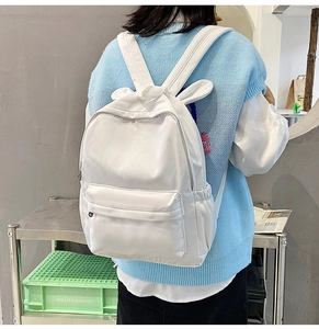 Rear view of a model wearing a white rabbit ear backpack with minimalist interior decor