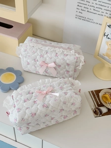 Detailed view of floral quilted makeup bags with white lace edges and pink ribbon bows