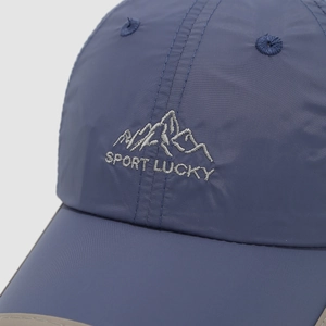 Detail van donkerblauwe sneldrogende pet met borduursel en Sport Lucky tekst