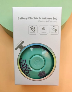 Detail showing the palm-sized, low noise electric nail trimmer in its white window packaging