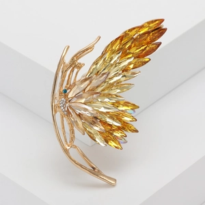 Elegant gold butterfly brooch with amber crystals on white geometric stand