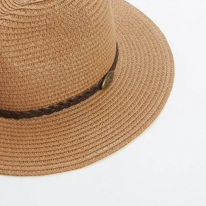 Detail of hand-woven straw hat with leather band and vintage bronze metal emblem