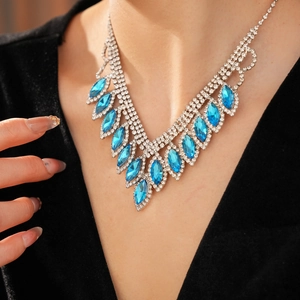 Close-up of elegant V-shaped necklace with blue marquise gemstones and crystals on model