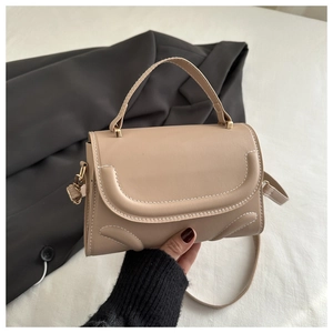 Detail of light brown leather handbag with contrast white stitching and gold hardware