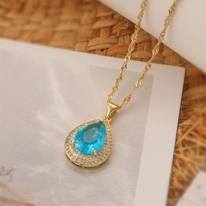 Macro shot of gold plated water drop necklace with sky blue stone and micro pavé zircons