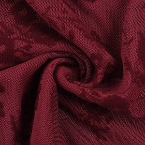 Vue détaillée du tissu en maille floquée bordeaux avec drapé souple et texture jacquard