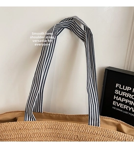 Detail of straw woven tote with blue and white striped fabric handles and texture