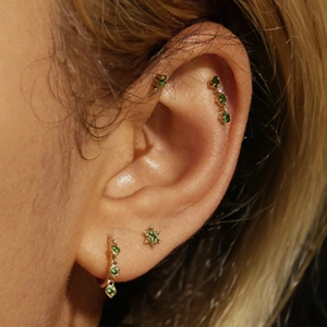 Detail of s925 silver gold floral earrings set with emerald green stones and opal accents