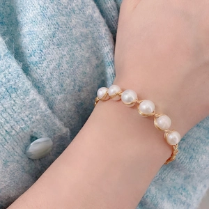 Elegant white freshwater pearl bracelet with handcrafted gold wire on a model wrist